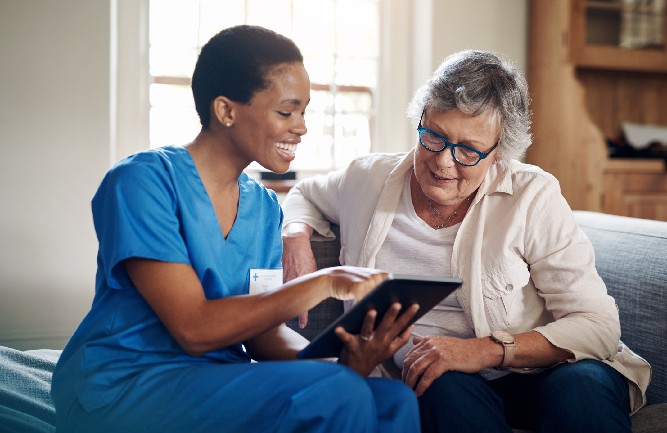 Nurse assists older patient with iPad